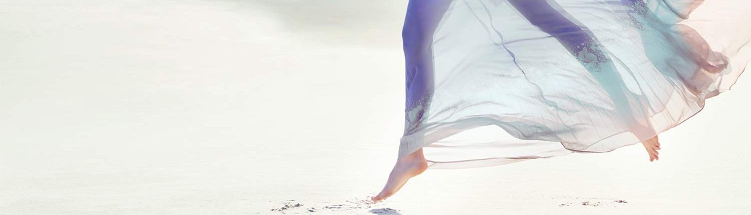 Side view of a beautiful young woman wearing a flowing dress in a sandy landscape